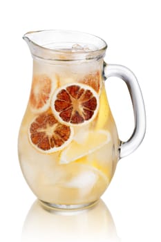 Jug of sparkling lemonade (spritzer). Carbonated iced water with lemon and dried orange wheels in a glass pitcher
