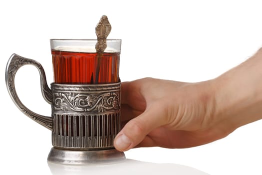 Man's hand holding a soviet faceted glass of tea (stakan) with teaspoon standing into vintage glass-holder (podstakannik)