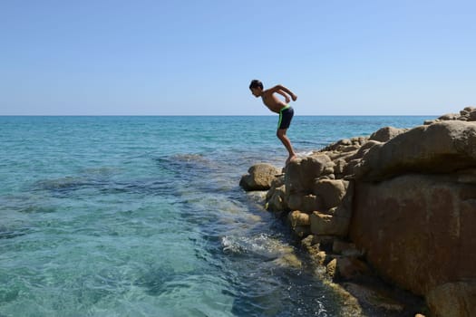 Carefree summer for the boy who dives from the rocks into the sea.