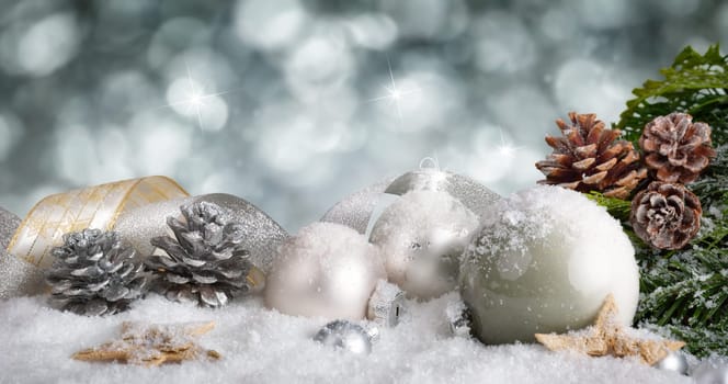 Elegant Christmas arrangement with snow covered silver baubles,nicely curved ribbons and pine cones,with glittering bokeh background