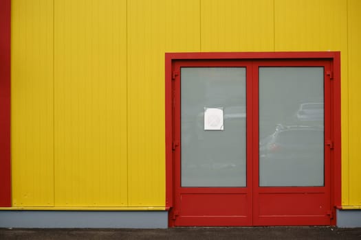 A colourful and distinctive side wall of a shopping centre with a side entrance and a bright colour.