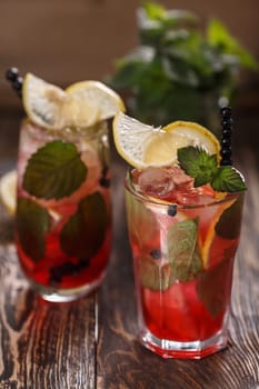 Two glasses of blueberry mojito cocktail on a wooden table