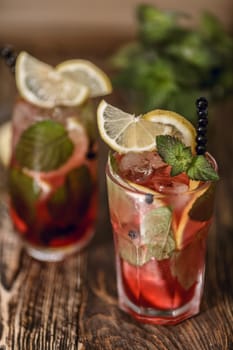 Two glasses of blueberry mojito cocktail on a wooden table