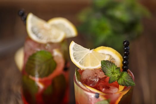 Two glasses of blueberry mojito cocktail on a wooden table