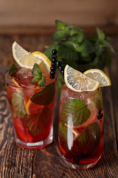 Two glasses of blueberry mojito cocktail on a wooden table