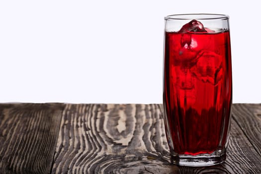 Iced hibiscus tea also known as Flor de Jamaica on wooden table  against plain background