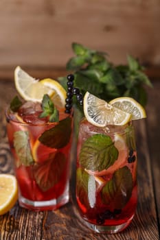 Two glasses of blueberry mojito cocktail on a wooden table