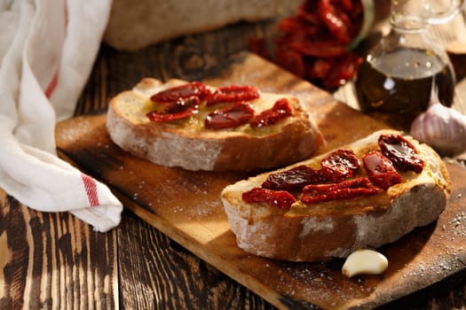Bruschetta with dried tomatoes, garlic and olive oil. Traditional Italian cuisine sandwich made of grilled ciabatta. Antipasti