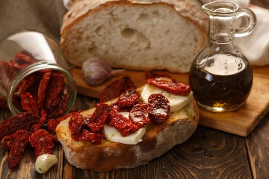 Bruschetta with dried tomatoes, mozzarella, garlic and olive oil. Traditional Italian cuisine sandwich made of grilled ciabatta. Antipasti