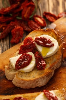 Bruschetta with dried tomatoes, mozzarella, garlic and olive oil. Traditional Italian cuisine sandwich made of grilled ciabatta. Antipasti