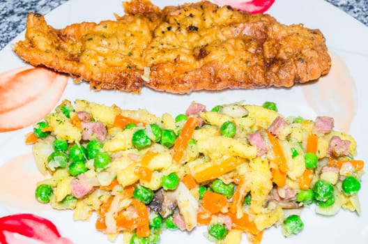 White plate with Spätzle and breaded roastfish.