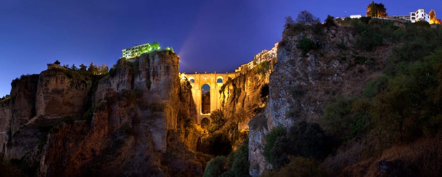 illuminated Puente Nuevo Bridge from outskirts of Ronda at sunset, Spain. HDR