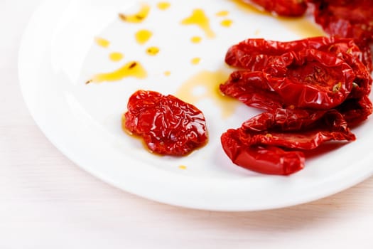 Sun dried tomatoes with olive oil on white plate
