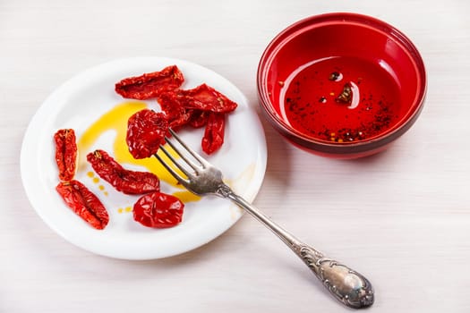 Sun dried tomatoes with olive oil on white plate