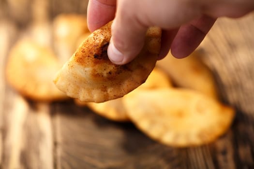 Male hand holding fried colombian empanada. Savory stuffed patties also known as pastel,pate or pirozhki