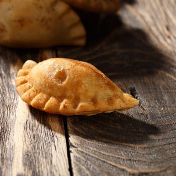 Fried colombian empanada on wooden table. Savory stuffed patty also known as pastel,pate or pirozhki