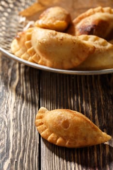 Fried colombian empanadas on wooden table. Savory stuffed patties also known as pastel,pate or pirozhki