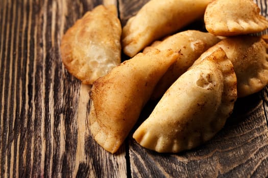 Fried colombian empanadas on wooden table. Savory stuffed patties also known as pastel,pate or pirozhki