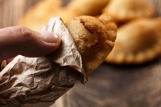 Male hand holding fried colombian empanada. Savory stuffed patties also known as pastel,pate or pirozhki