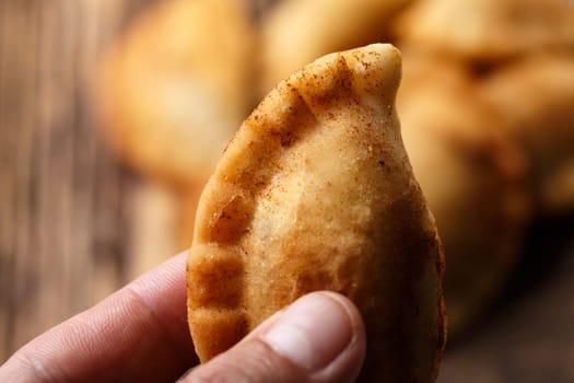 Male hand holding fried colombian empanada. Savory stuffed patties also known as pastel,pate or pirozhki