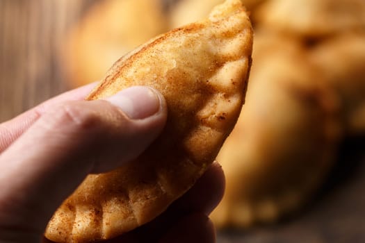 Male hand holding fried colombian empanada. Savory stuffed patties also known as pastel,pate or pirozhki