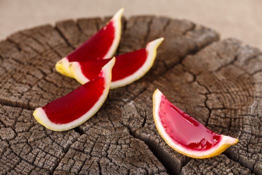 Lemon tequila strawberry jelly (jello) shots on a old wooden wheel. Unusual adult party drinks