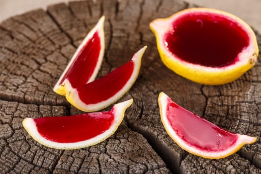 Lemon tequila strawberry jelly (jello) shots on a old wooden wheel. Unusual adult party drink