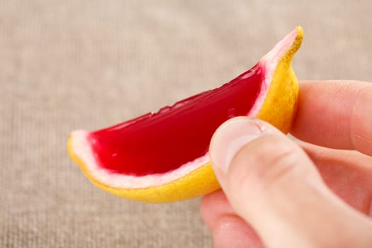 Male hand holding a lemon tequila strawberry jelly (jello) shot. Selective focus on a shooter