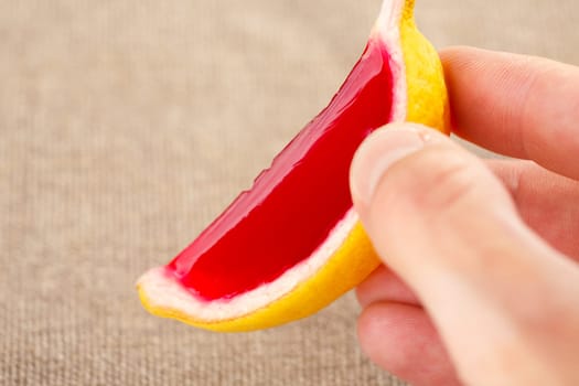 Male hand holding a lemon tequila strawberry jelly (jello) shot. Selective focus on a shooter