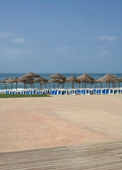 Rustic umbrellas made of natural fibers and sunbeds at Costa del Sol, Spain