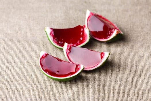 Watermelon like tequila  jelly (jello) shots made out of carved lime on linen tablecloth. Unusual adult party drinks