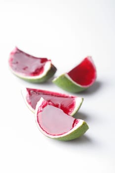 Watermelon like tequila  jelly (jello) shots made out of carved lime on white. Unusual adult party drinks