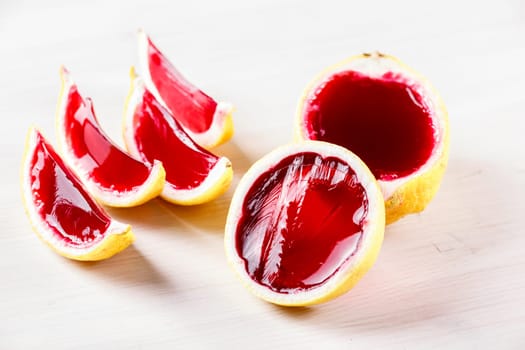 Vodka  jelly (jello) shots made out of carved lemon on bleached wooden tablel. Unusual adult party drinks
