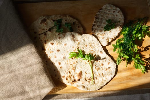 Indian naan bread on wooden table next to greens