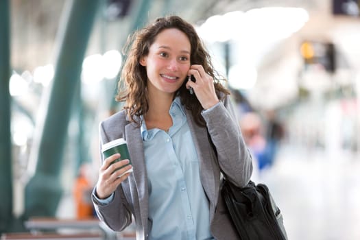 View of a Young attractive business woman using smartphone drinking coffee