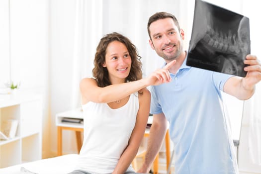 View of a Young attractive physiotherapist analysing X-ray with patient