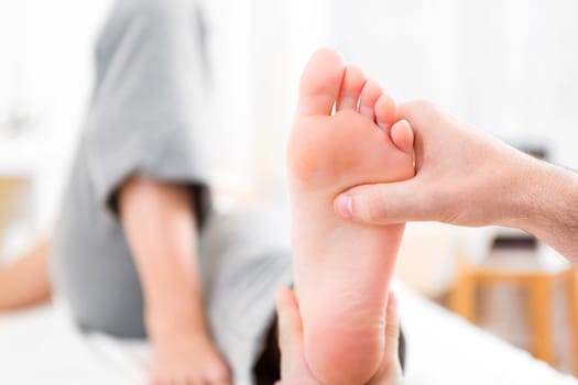 View of a Young attractive physiotherapist doing reflexology on a patient feet