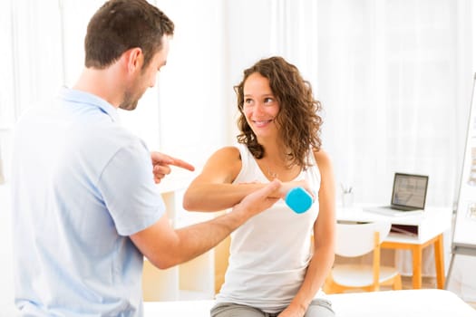 View of a Young attractive woman doing exercise with physiotherapist