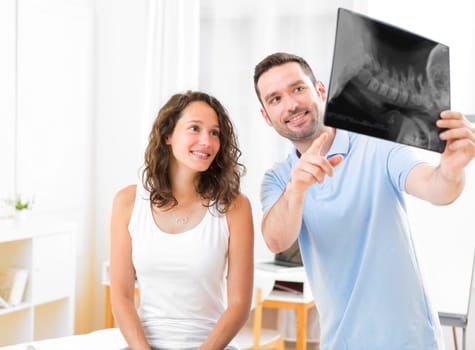 View of a Young attractive physiotherapist analysing X-ray with patient