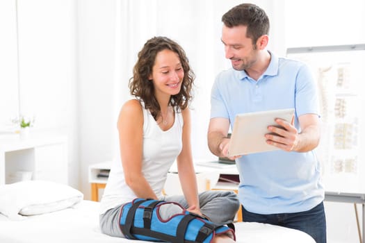 View of a Young attractive physiotherapist using tablet with patient