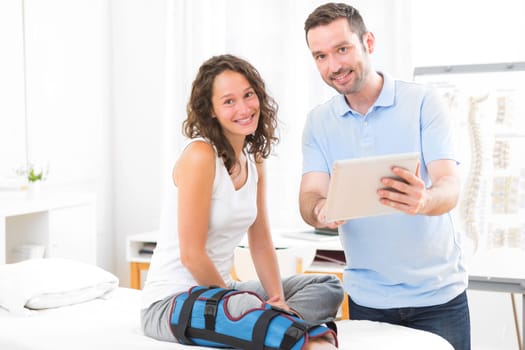 View of a Young attractive physiotherapist using tablet with patient
