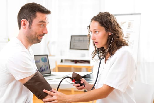 View of a Young attractive doctor checking patient's blood pressure