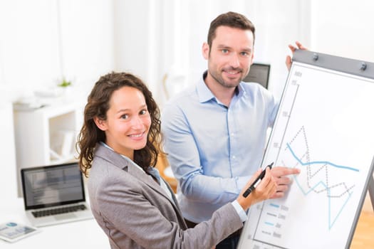 View of  Business man and woman analysing stats on a paperboard