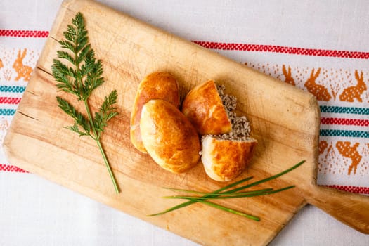 Russian pirozhki (baked patties) on wooden cutboard
