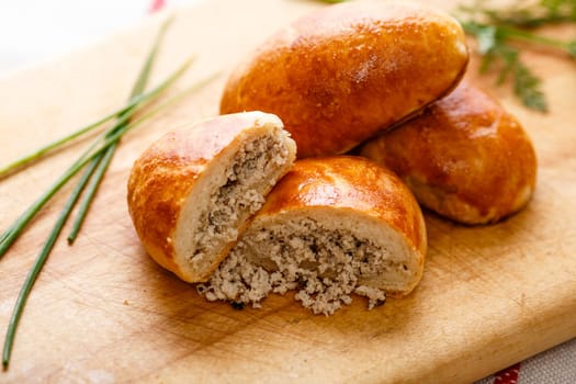 Russian pirozhki (baked patties) on wooden cutboard