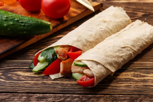 Traditional shawarma wrap with chicken and vegetables near its ingredients