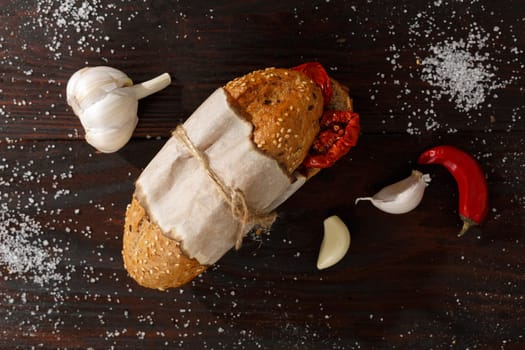 Ingredients for whole grain sandwich with sun dried tomatoes, chili and garlic on dark burnished wooden table. Top view