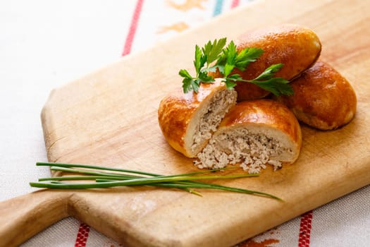 Russian pirozhki (baked patties) on wooden cutboard