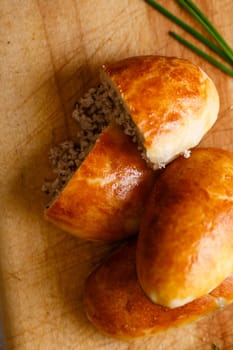 Russian pirozhki (baked patties) on wooden cutboard