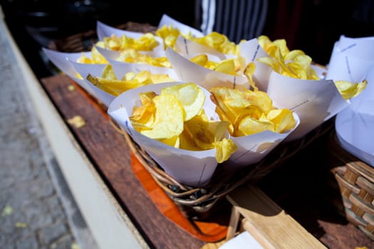 Fried potato chips  in paper cornets for sell at market stall on wicker basket